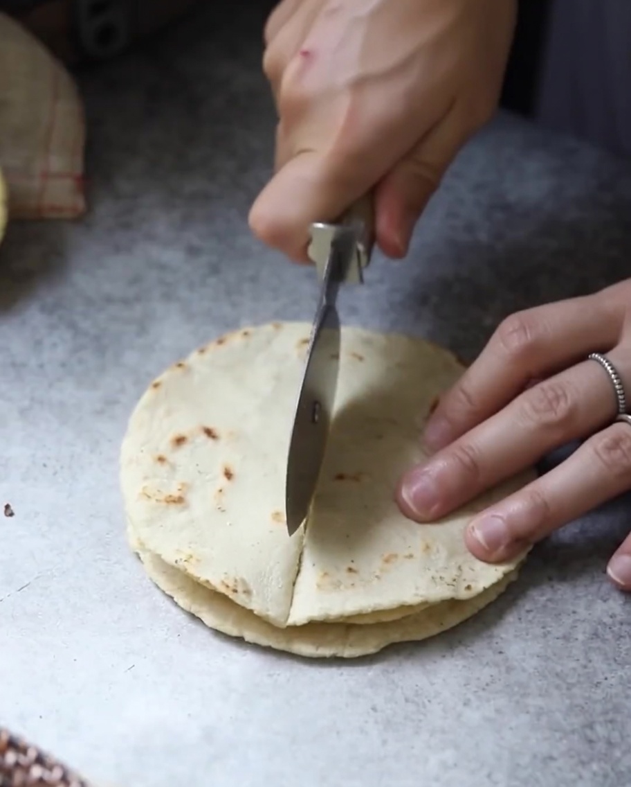 Gestapelte, gebackene Tortilla-Fladenbrote werden mit einer Klinge in dreieckige Stücke geschnitten.