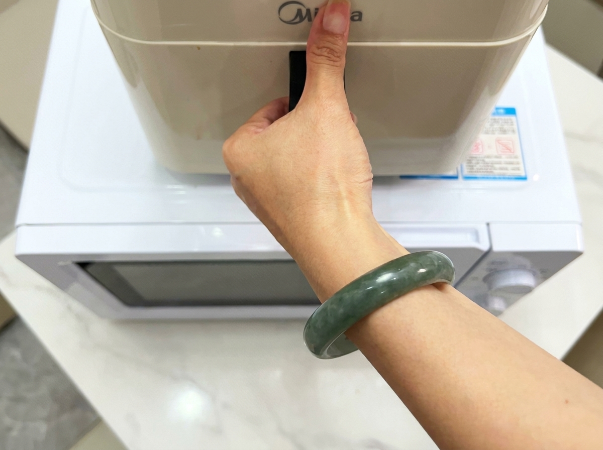Eine Hand hält den Griff eines modernen Küchengeräts auf einer weißen Oberfläche.