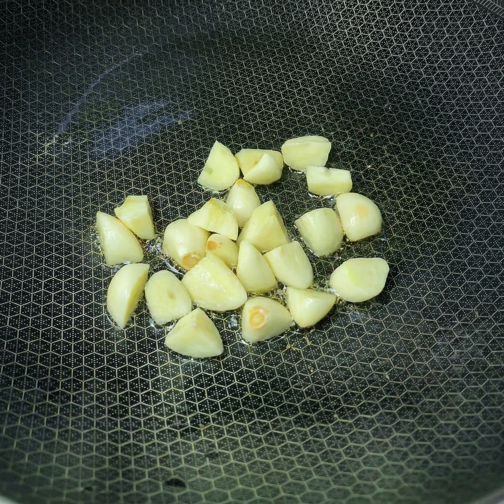 Knoblauchzehen braten in einem Wok mit heißem Öl an.