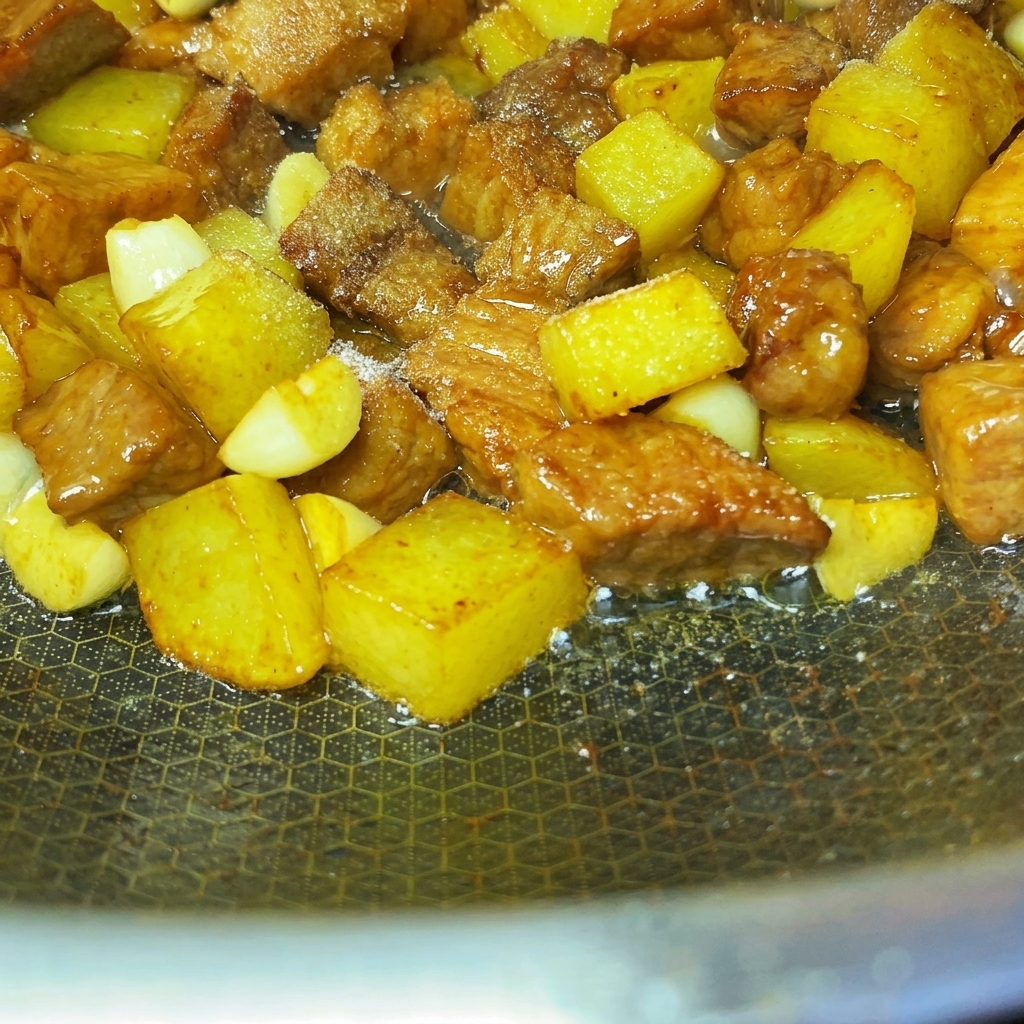 Gewürze und Sesamsamen gleichmäßig über die gebratenen Schweine- und Kartoffelwürfel gestreut.