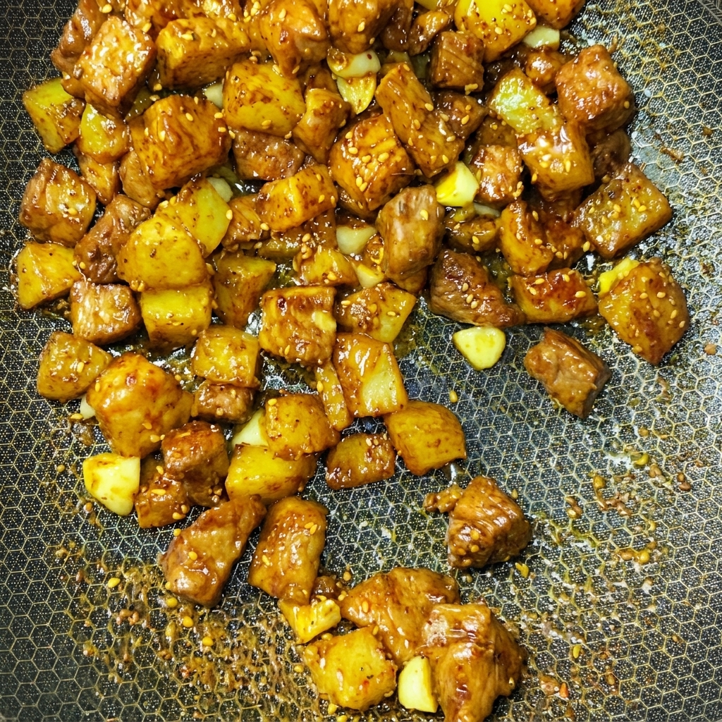 Schweinefleisch- und Kartoffelwürfel werden dynamisch mit Gewürzen in einem Wok geschwenkt.