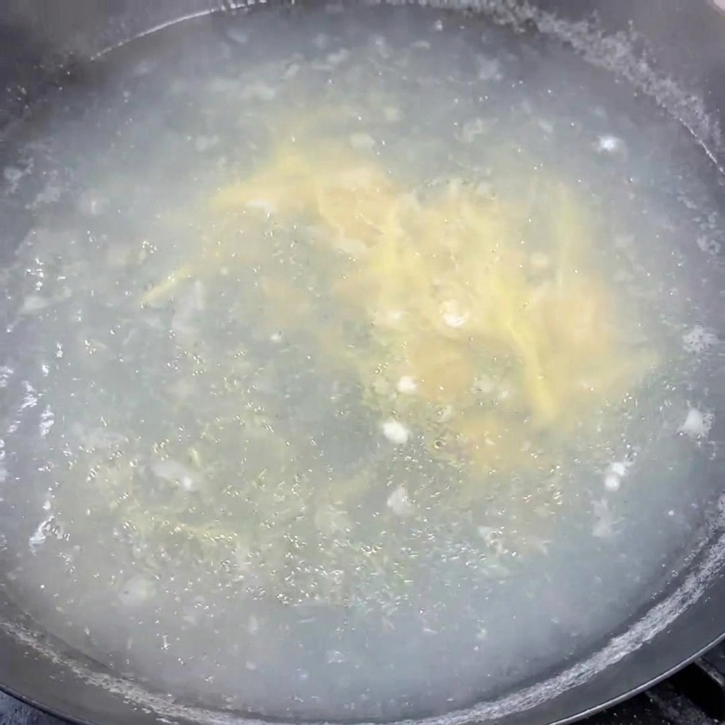 Frisch gehackte Frühlingszwiebeln werden in einen Topf mit heißer, köchelnder Suppe eingerührt.