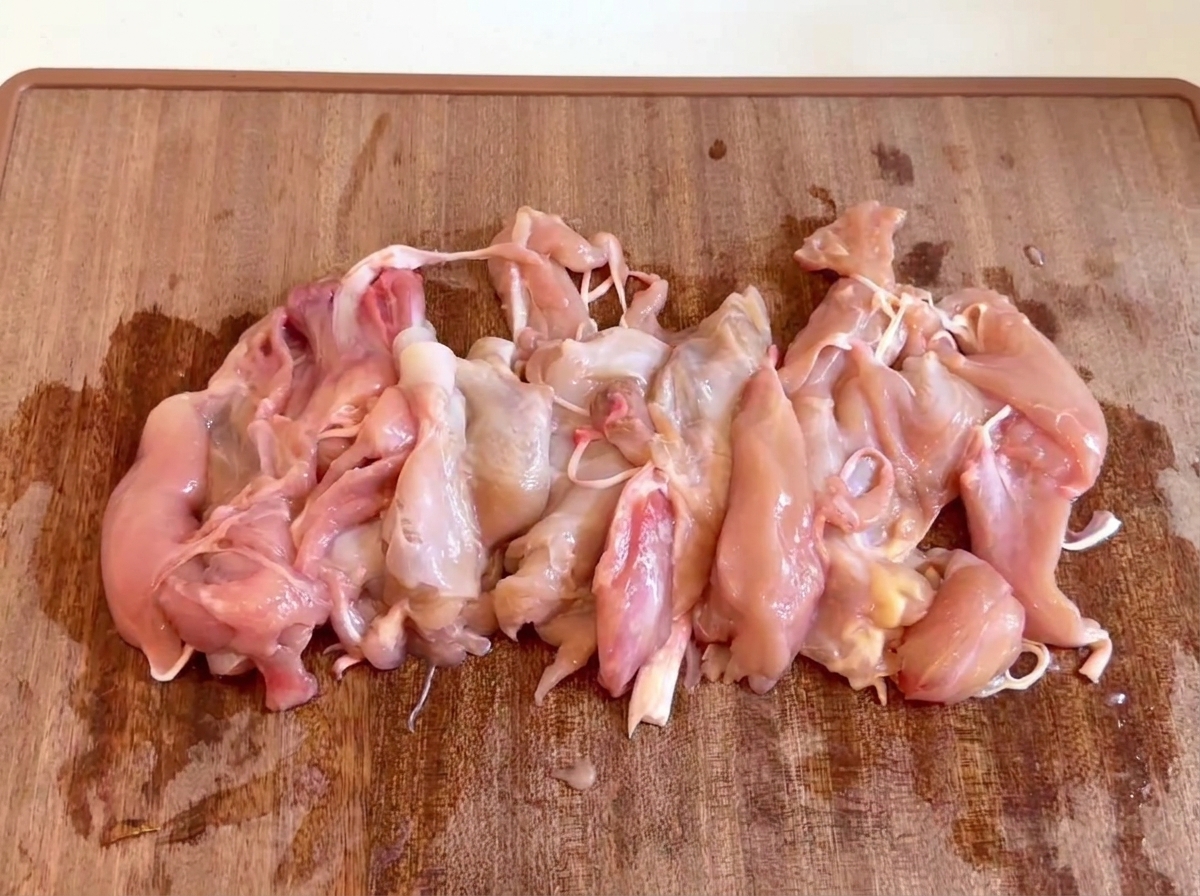 Rohe, entbeinte Hähnchenfleischstücke auf einem Holzschneidebrett zusammengelegt.
