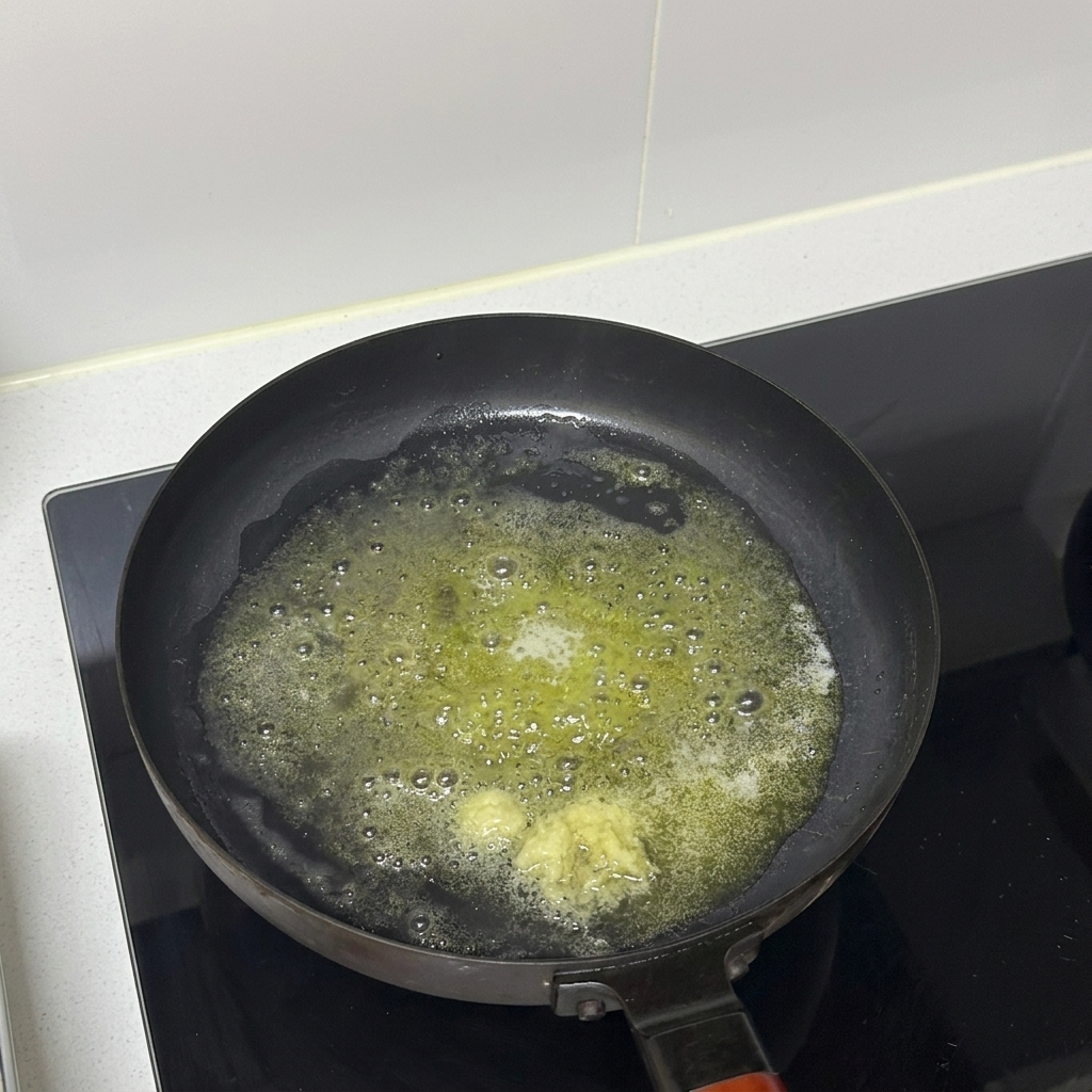 Gehackter Knoblauch gart in geschmolzener Butter in einer Bratpfanne.