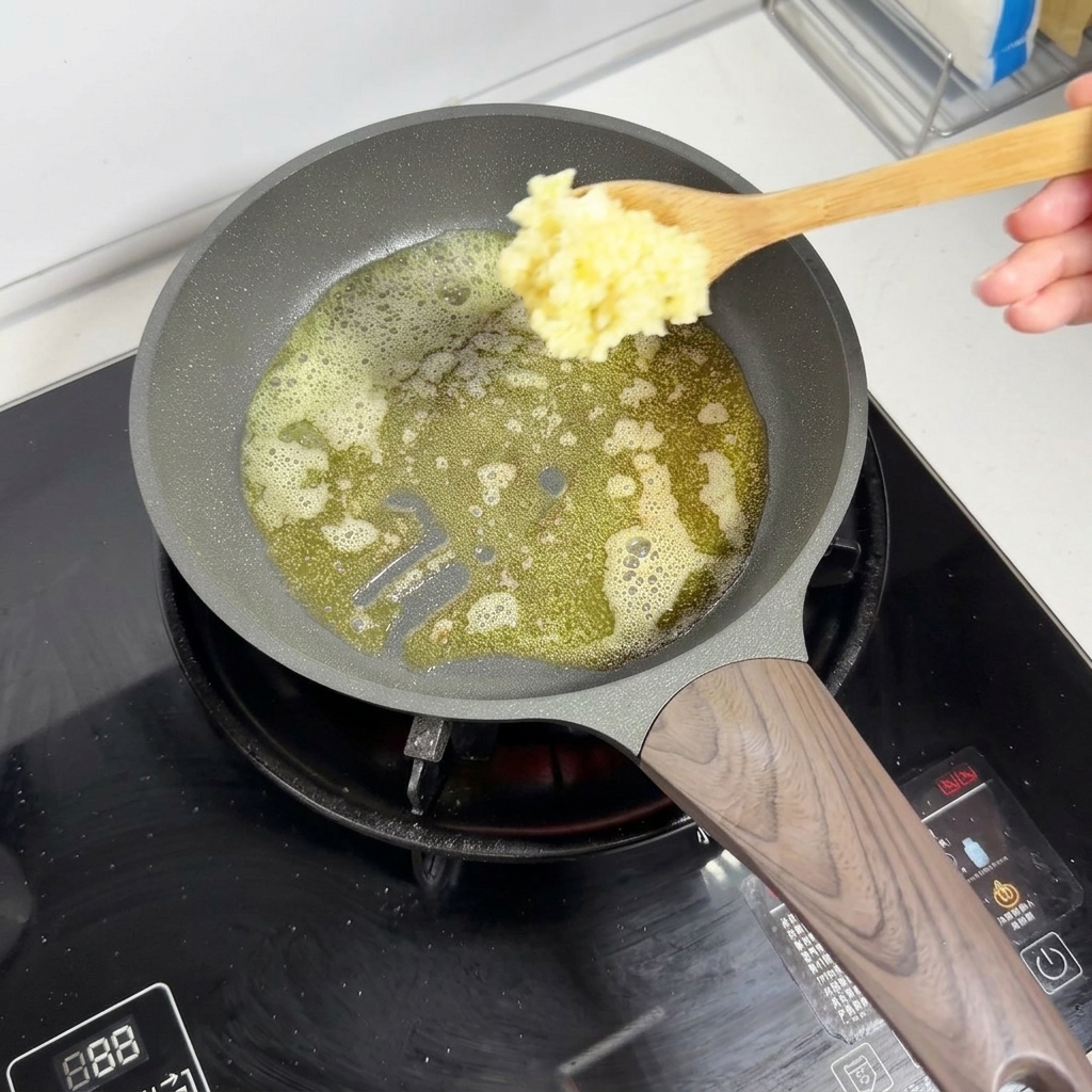 Ein Holzlöffel gibt gehackten Knoblauch in die schmelzende, schäumende Butter in einer Pfanne.
