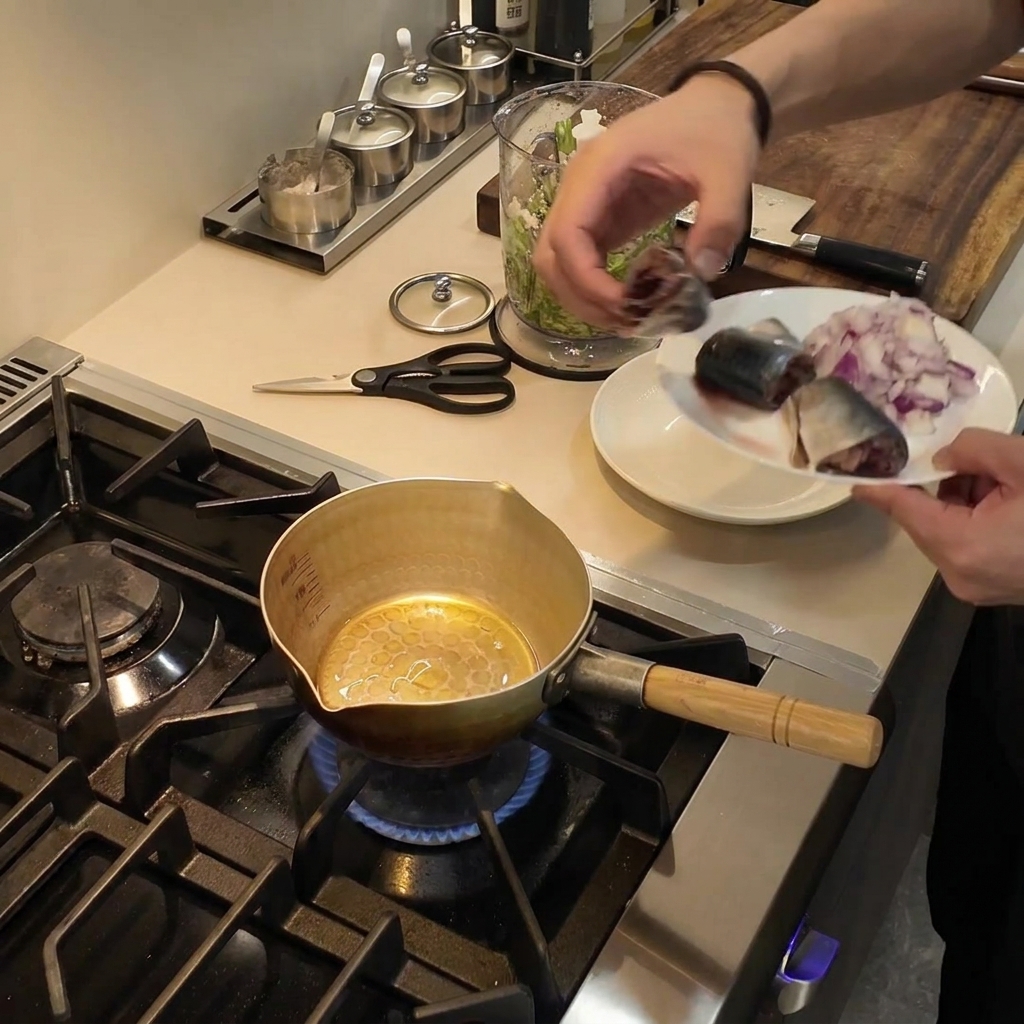 Ein kleiner goldener Topf steht auf einer Gaskochstelle, während Speiseöl darin schimmert.