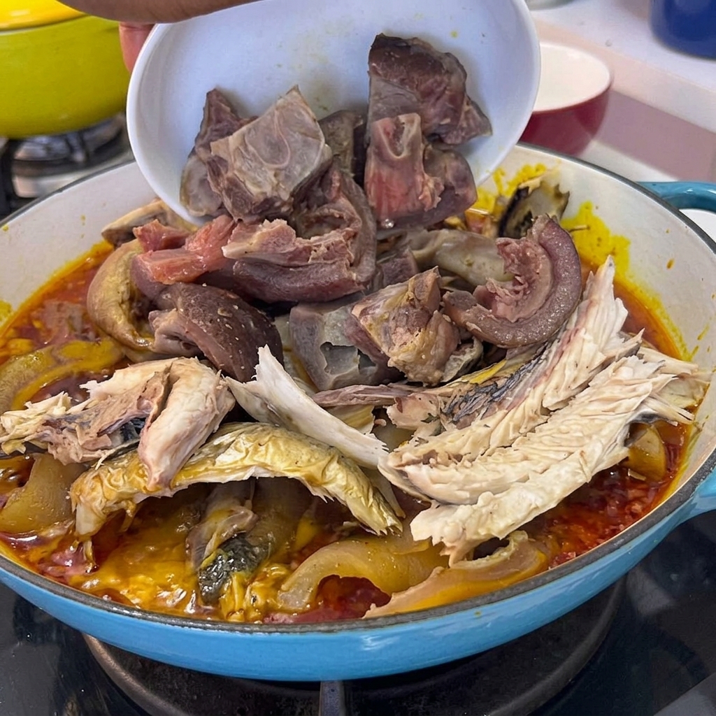 Gekochte Schweinefleischstücke werden aus einer Schüssel in den Topf mit Fisch und Sauce gegeben.