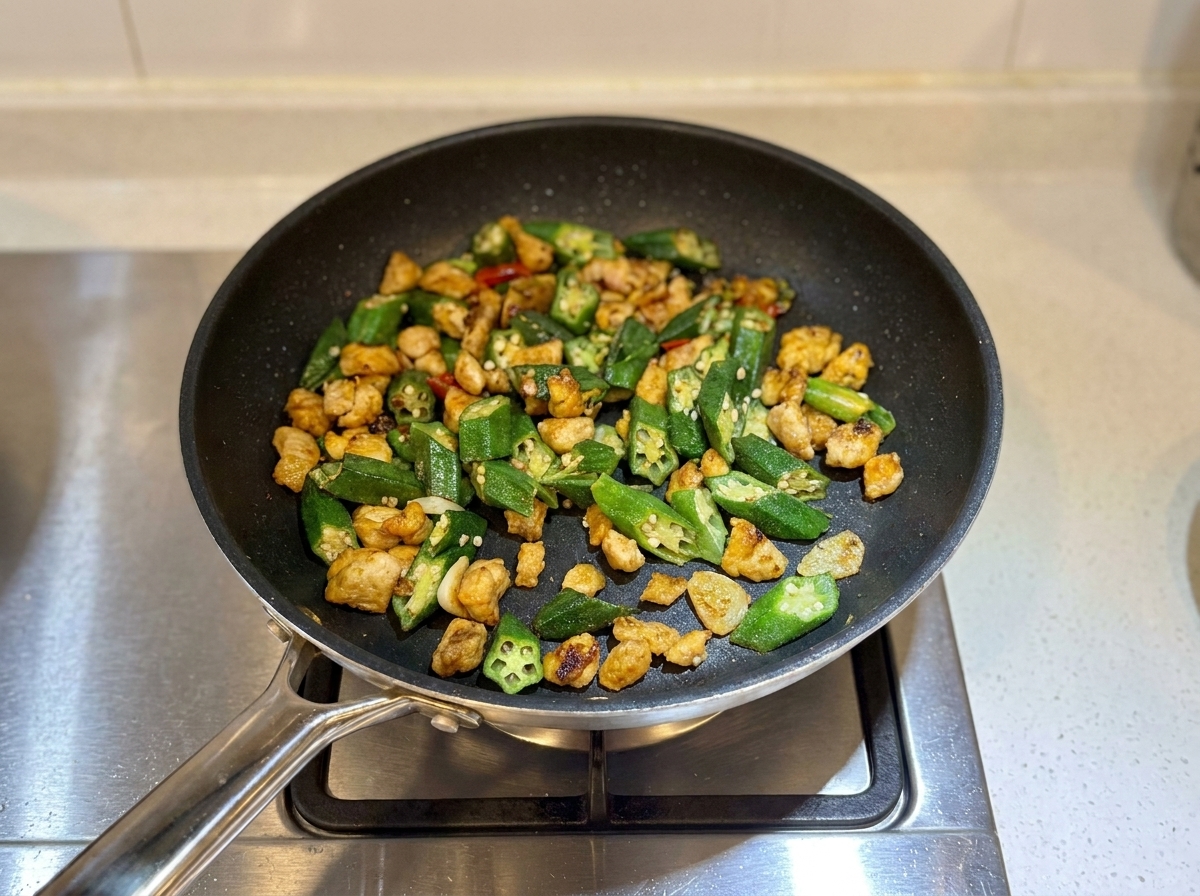 Fertiges Hähnchen-Okra-Pfannengericht in der Pfanne, sieht etwas trocken aus und ist servierbereit.