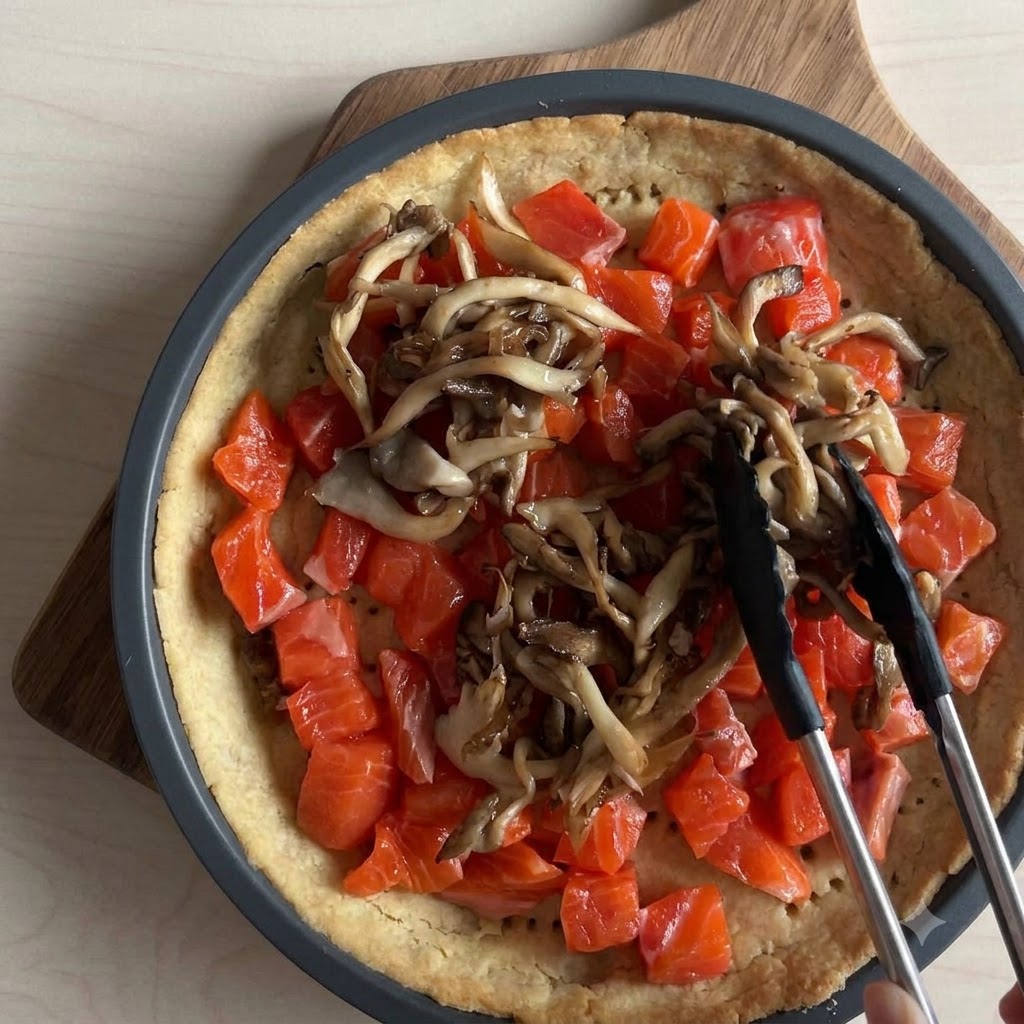 Handgezupfte Stücke von frischem Mozzarella werden über eine Lachs-Pilz-Tarte-Füllung gestreut.