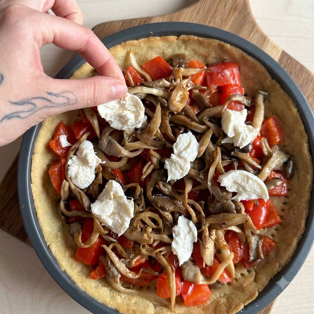Sahne wird über eine mit Lachs, Pilzen und Mozzarella gefüllte Tarte gegossen.
