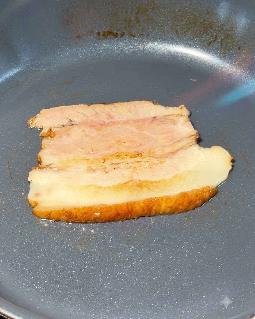 Chashu-Schweinebauchscheiben werden in einer Pfanne mit einem Küchenbrenner flambiert.