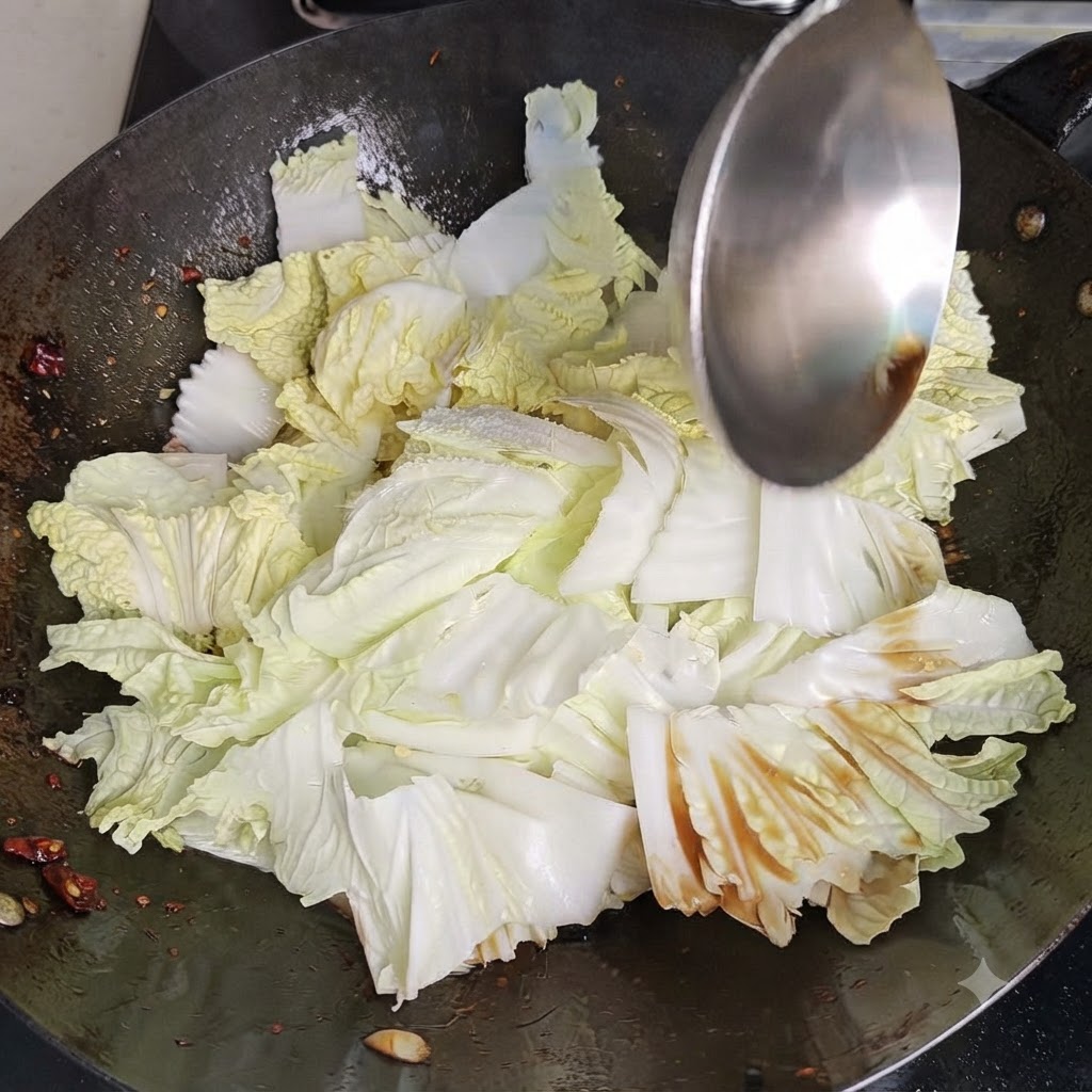 Ein Wok-Spatel wirbelt und rührt Chinakohl und Gewürze kräftig in einem heissen Wok um.