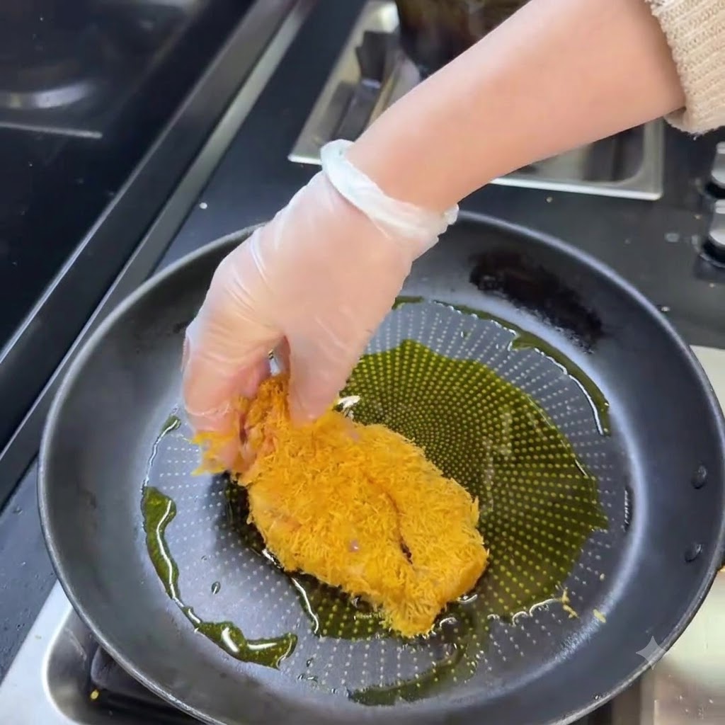 Ein paniertes Schweineschnitzel brät in einer Pfanne mit heißem Öl goldbraun an.
