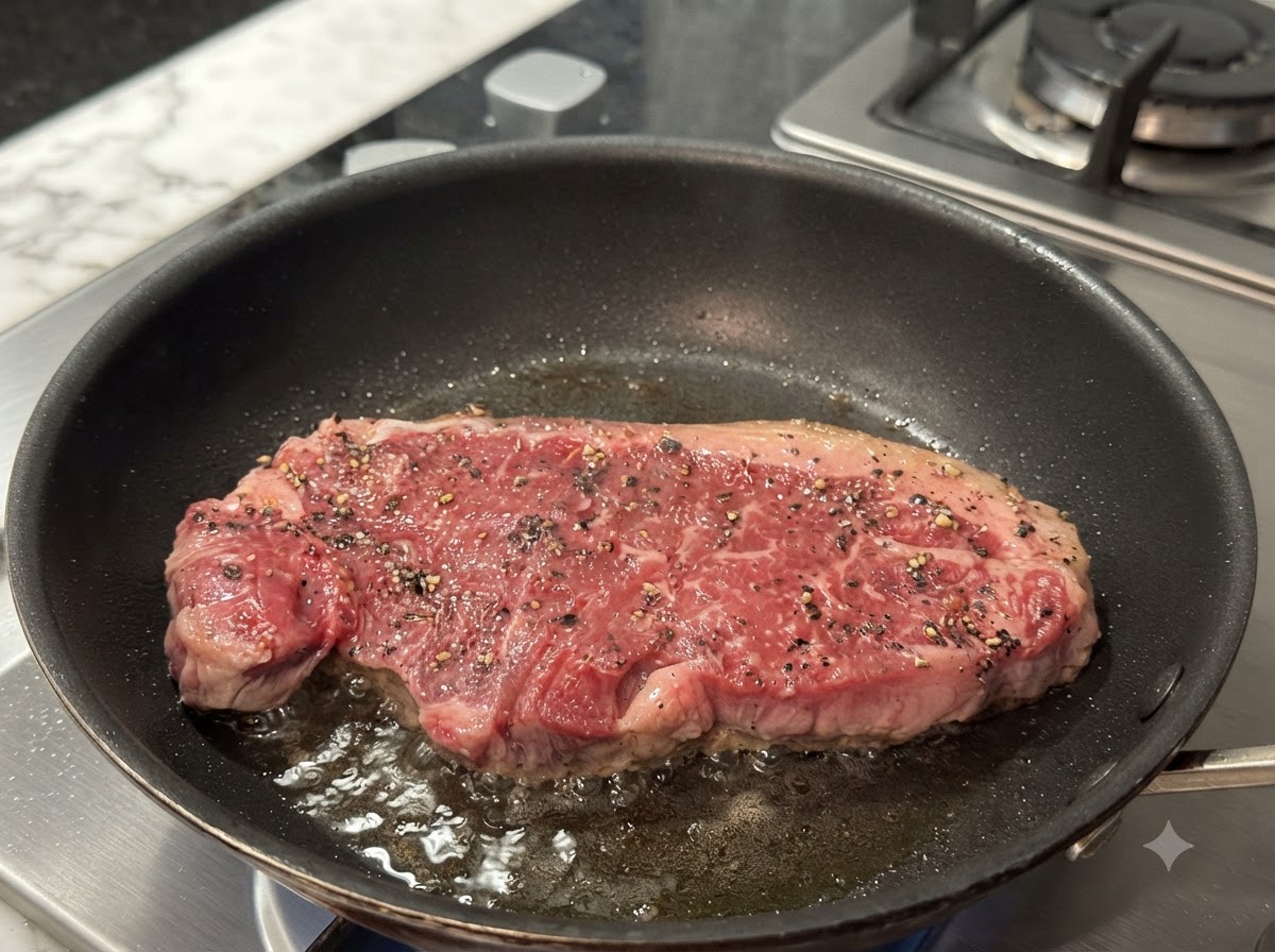 Ein Steak brät in einer heißen Pan und bildet eine gebräunte Kruste.