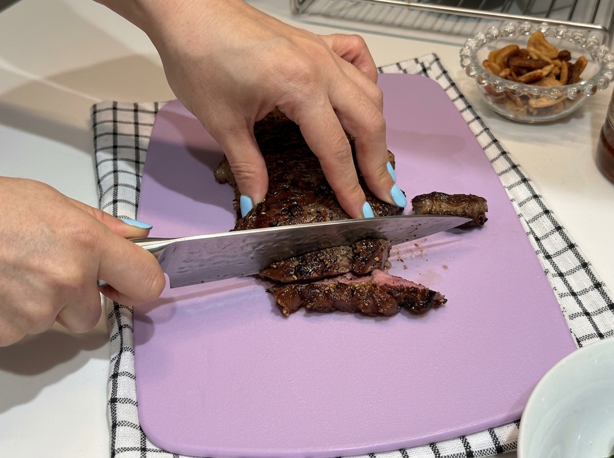 Steak wird auf einem lila Schneidebrett in Scheiben geschnitten.