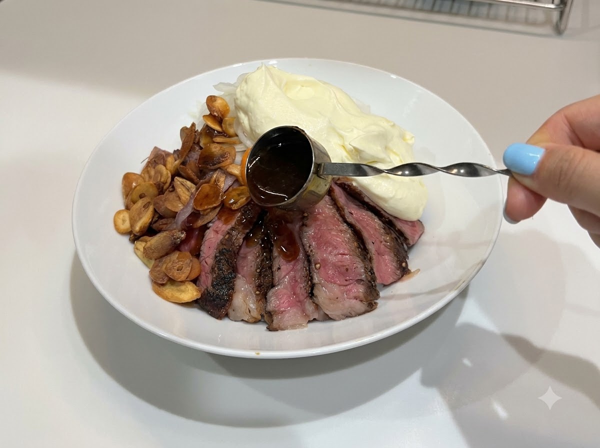 Dunkle, glänzende Teriyakisauce wird über die fertiggestellte Steak-Reis-Schüssel geträufelt.