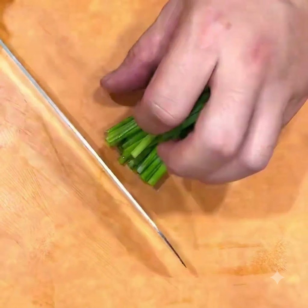Frühlingszwiebeln werden auf einem Holzbrett mit einem Messer fein gehackt.