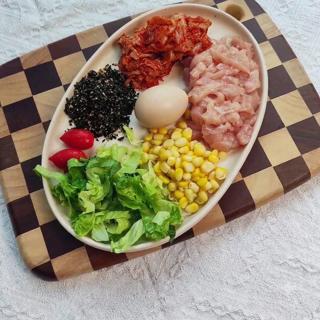 Gewürfelte Hähnchenbrust in einer Schüssel, vermischt mit Gewürzen, Ingwer und Knoblauch.