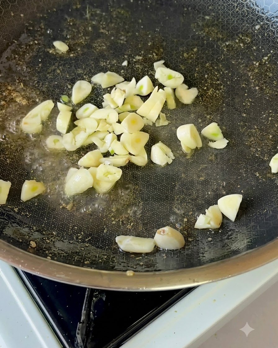 Frische Knoblauchscheiben, die sanft in Speiseöl in einer beschichteten Pfanne braten.