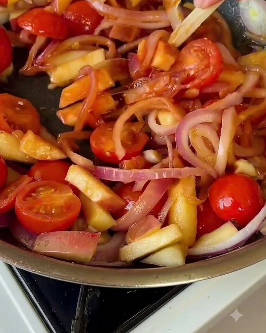 Chinakohl, der mit Tomaten und Zwiebeln in der Pfanne vermischt wird.
