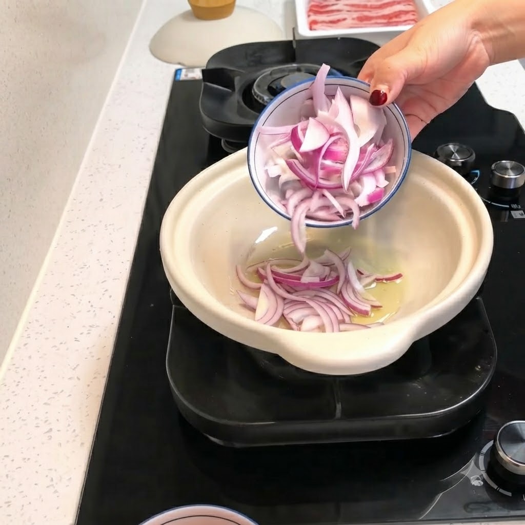 Rote Zwiebelstreifen und geschälte Tomatenstücke werden aus einer kleinen Schüssel in einen heißen Tontopf mit Öl gegeben.