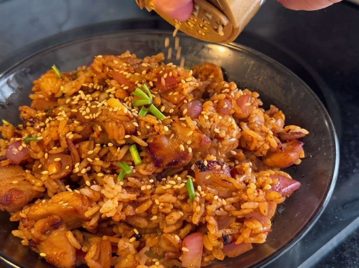 Kimchi wird in die Pfanne gegeben und zusammen mit Hähnchen und Zwiebeln gebraten.