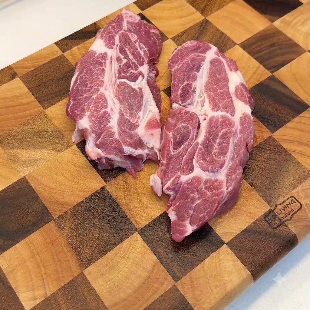 Rohe Schweineschulter wird mit einem Fleischklopfer aus Metall auf einem Holzschneidebrett plattiert.