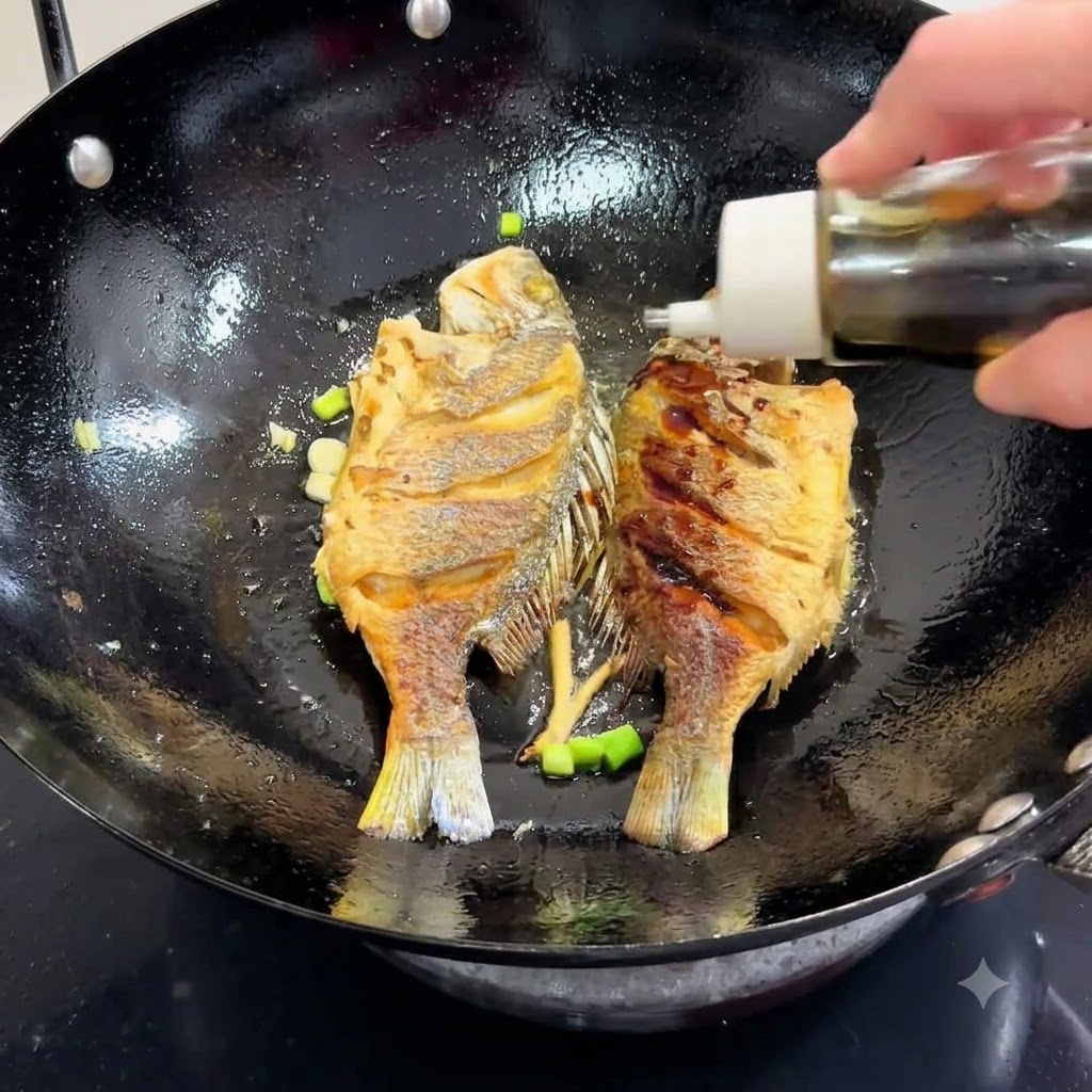 Sojasauce wird aus einer Flasche in einen Wok mit gebratenem Fisch und Frühlingszwiebeln gegossen.