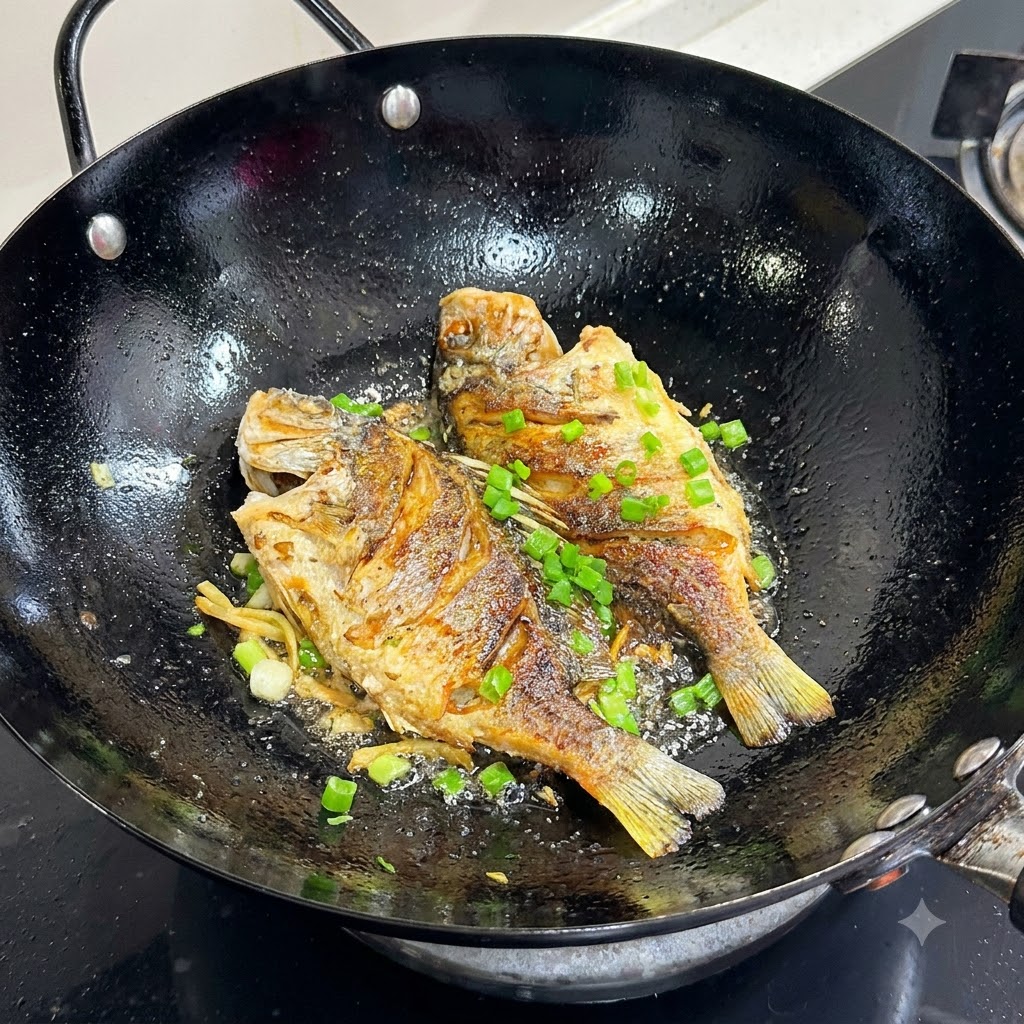 Gehackte Frühlingszwiebeln werden auf den goldbraun gebratenen Fisch in einem schwarzen Wok gestreut.