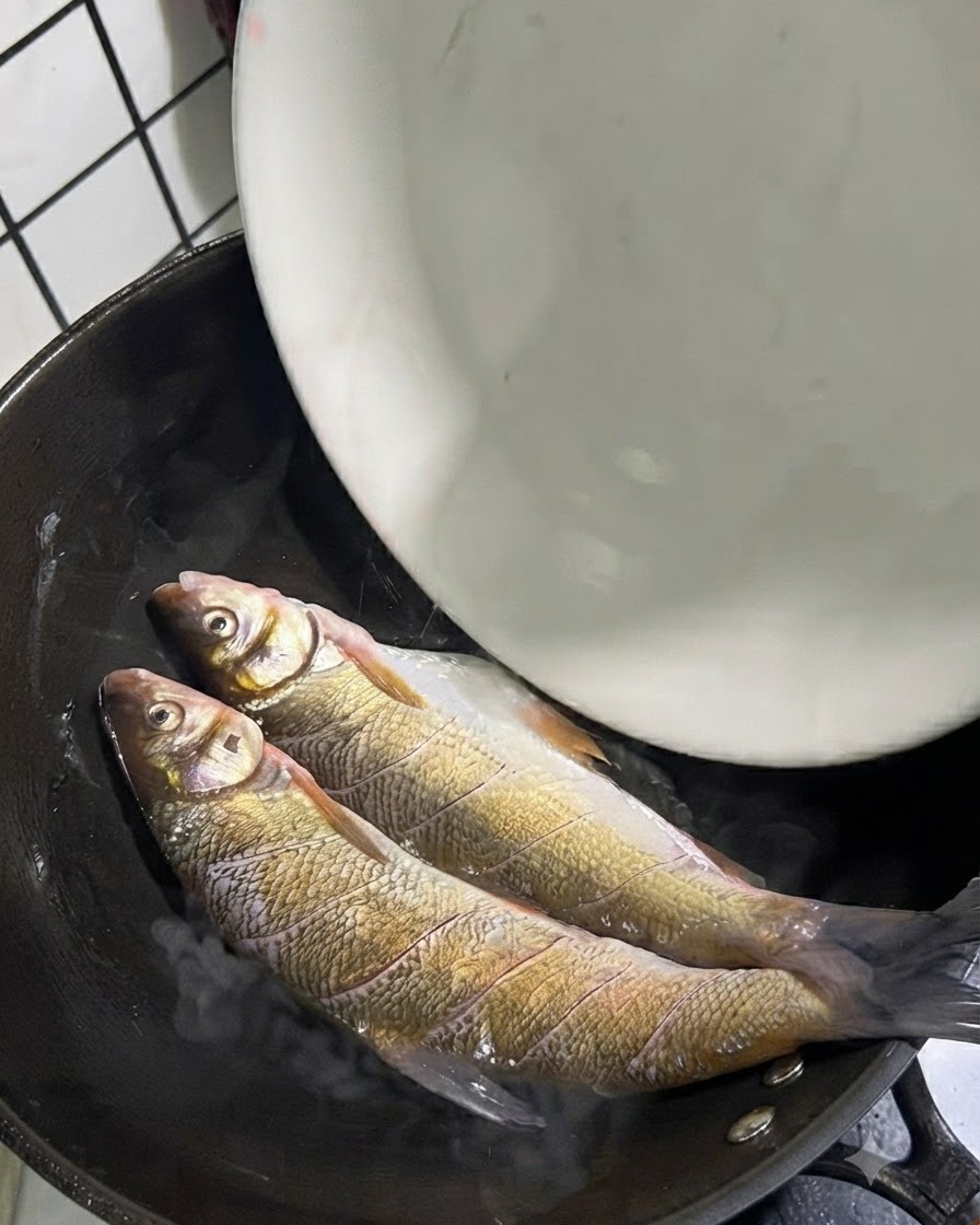Zwei ganze Gelbschwanzfische in einem heißen Wok mit Öl.