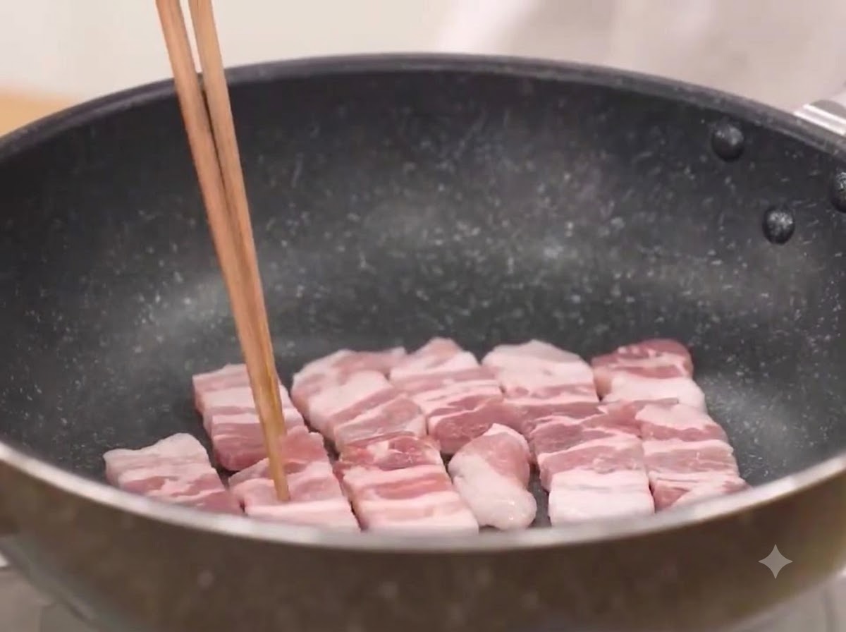 Schweinebauchscheiben werden in einer heißen Pfanne angebraten, bis sie brutzeln.