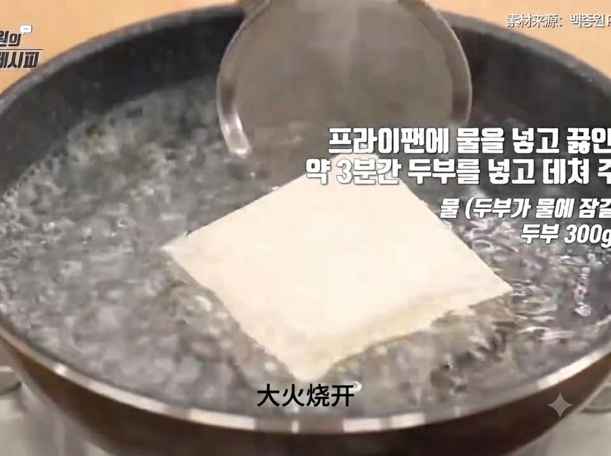 Ein fester Tofu-Block wird während des Blanchiervorgangs in einen Topf mit sprudelnd kochendem Wasser getaucht.