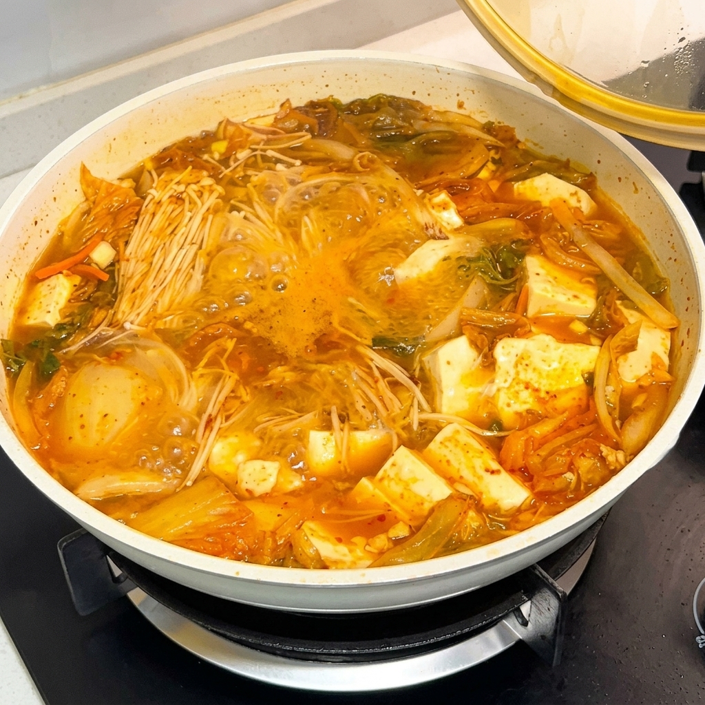 Ein Löffel koreanische Chilipasten-Sauce wird in einen köchelnden Suppentopf gegeben.