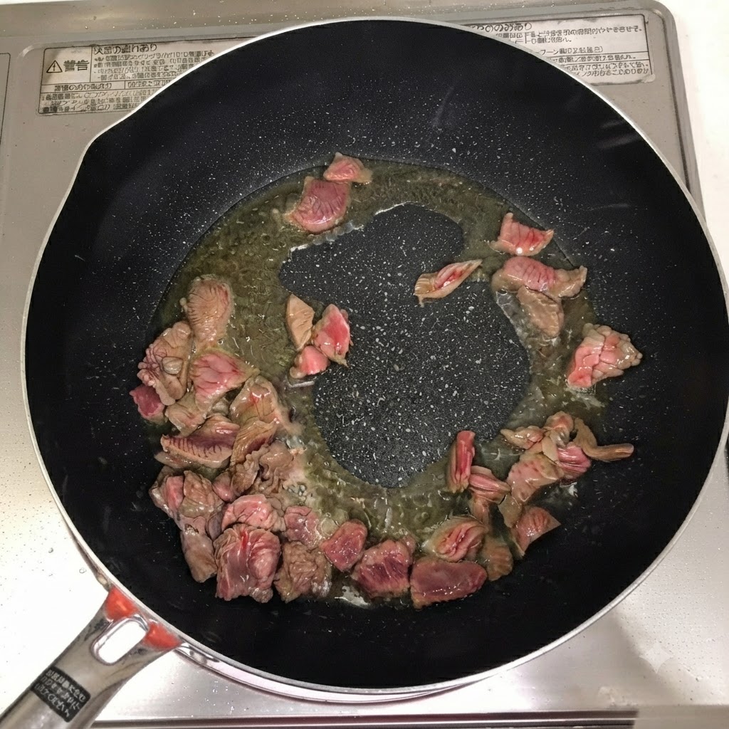 Kochwein, Chilipulver und Chilipaste werden ueber dem Rindfleisch in der Pfanne hinzugefuegt.