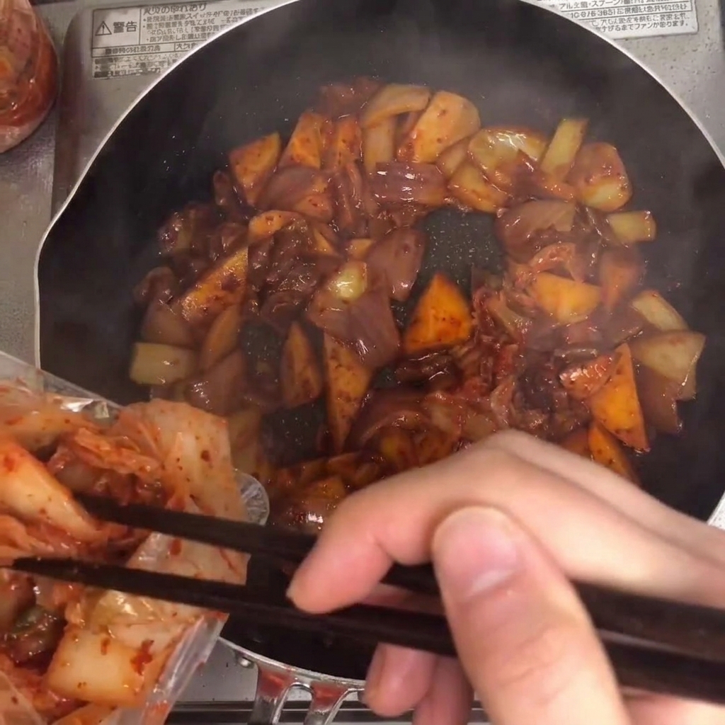 Kimchi wird in die Pfanne gegeben und mit den anderen Zutaten vermischt.