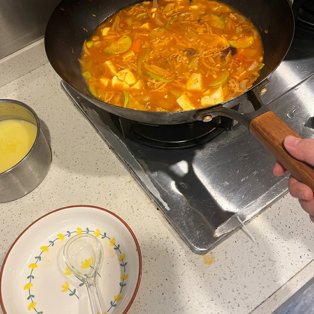 Koreanische Chilipaste wird in einen köchelnden Topf mit würziger Suppe mit Gemüse und Fleisch eingerührt.