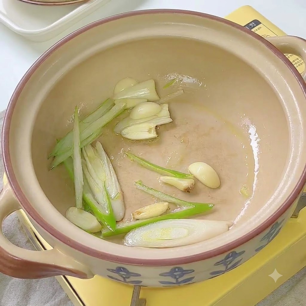 Kimchi wird zusammen mit Frühlingszwiebeln und Knoblauch in einem Keramiktopf angebraten.