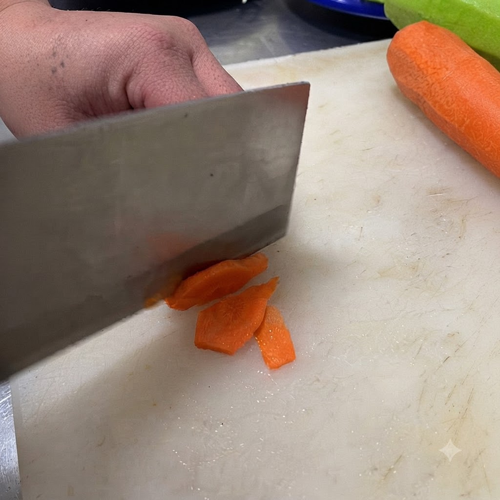 Ein Messer schneidet eine grüne Chilischote auf einem weißen Schneidebrett in Scheiben.