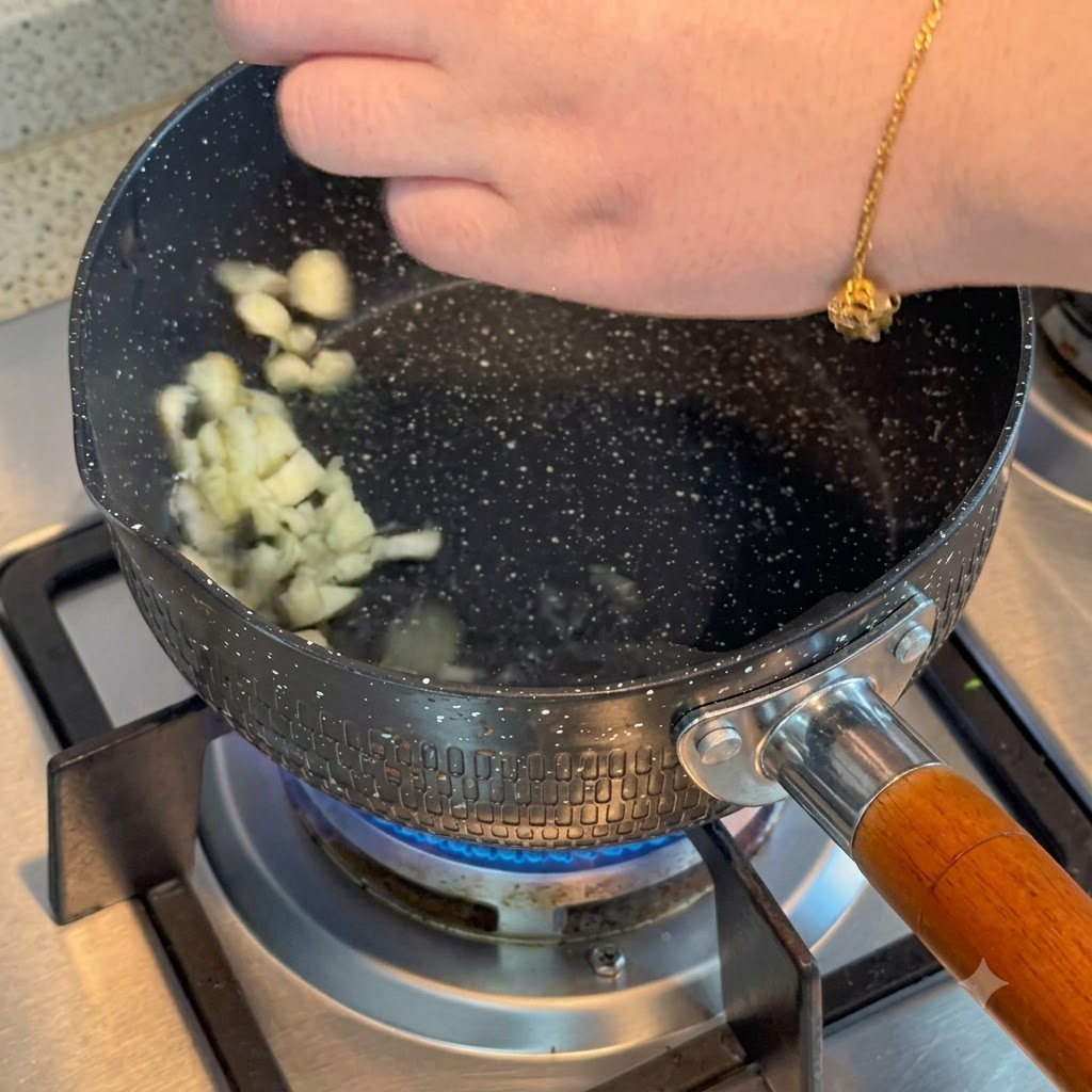 In Scheiben geschnittener Knoblauch brutzelt in heißen Öl in einem Topf auf einem Gasherd.