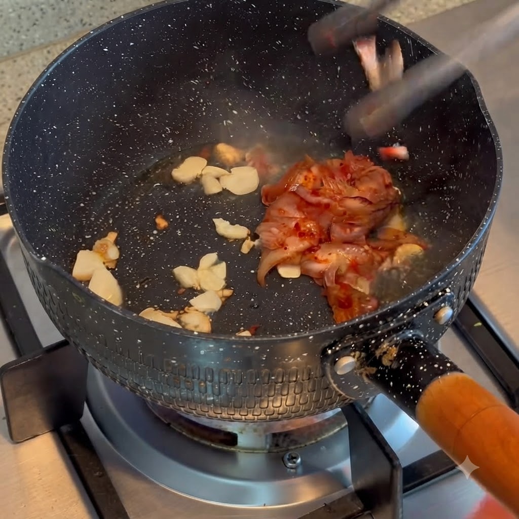 Kimchi wird mit gebratenem Knoblauch in einem Kochtopf vermengt und angebraten.