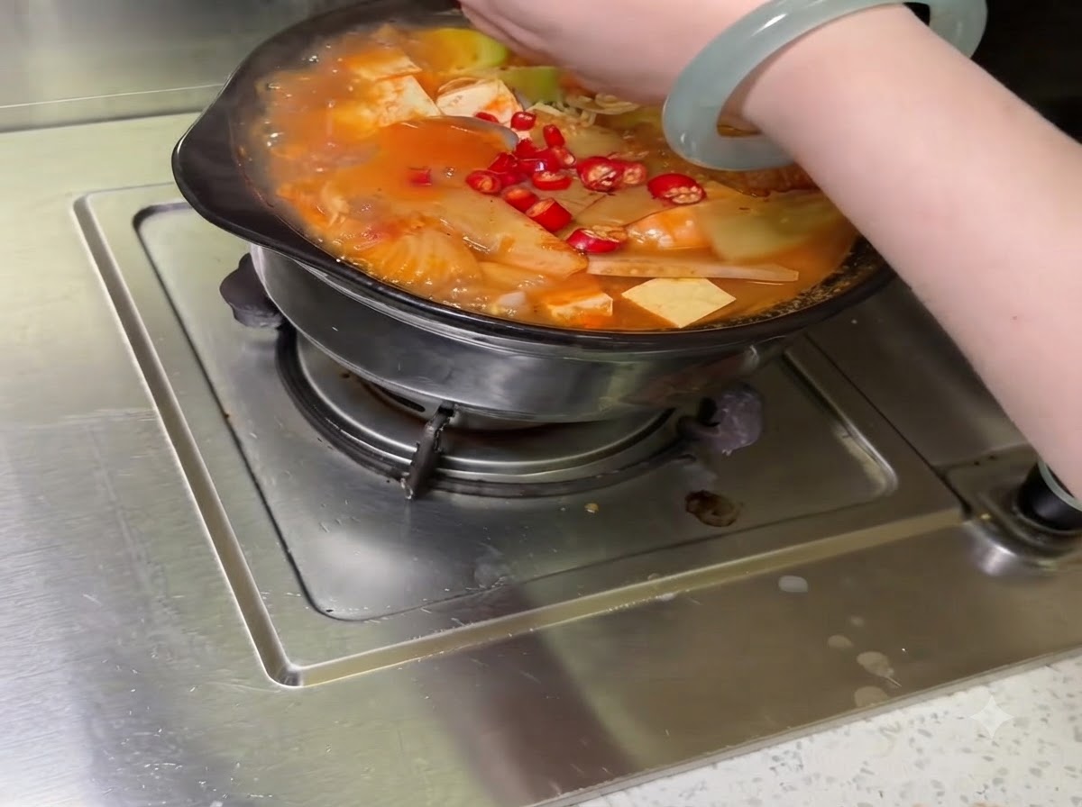 Verschiedenes geschnittenes Gemüse und Chilischoten werden im Kochtopf angeordnet.