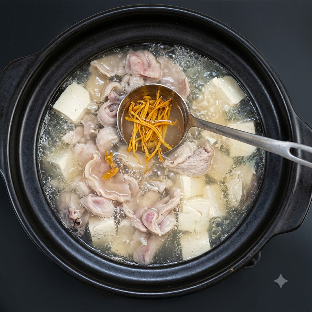 Frisch gehackte Frühlingszwiebeln werden über die köchelnde Suppe im Tonkrug gestreut.