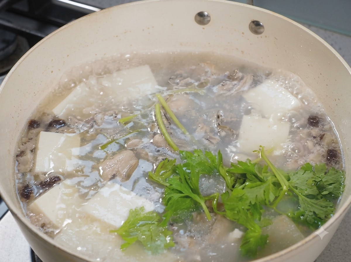 Frische Sellerieblätter werden über einen brodelnden Topf mit Austern-Tofu-Suppe gestreut.