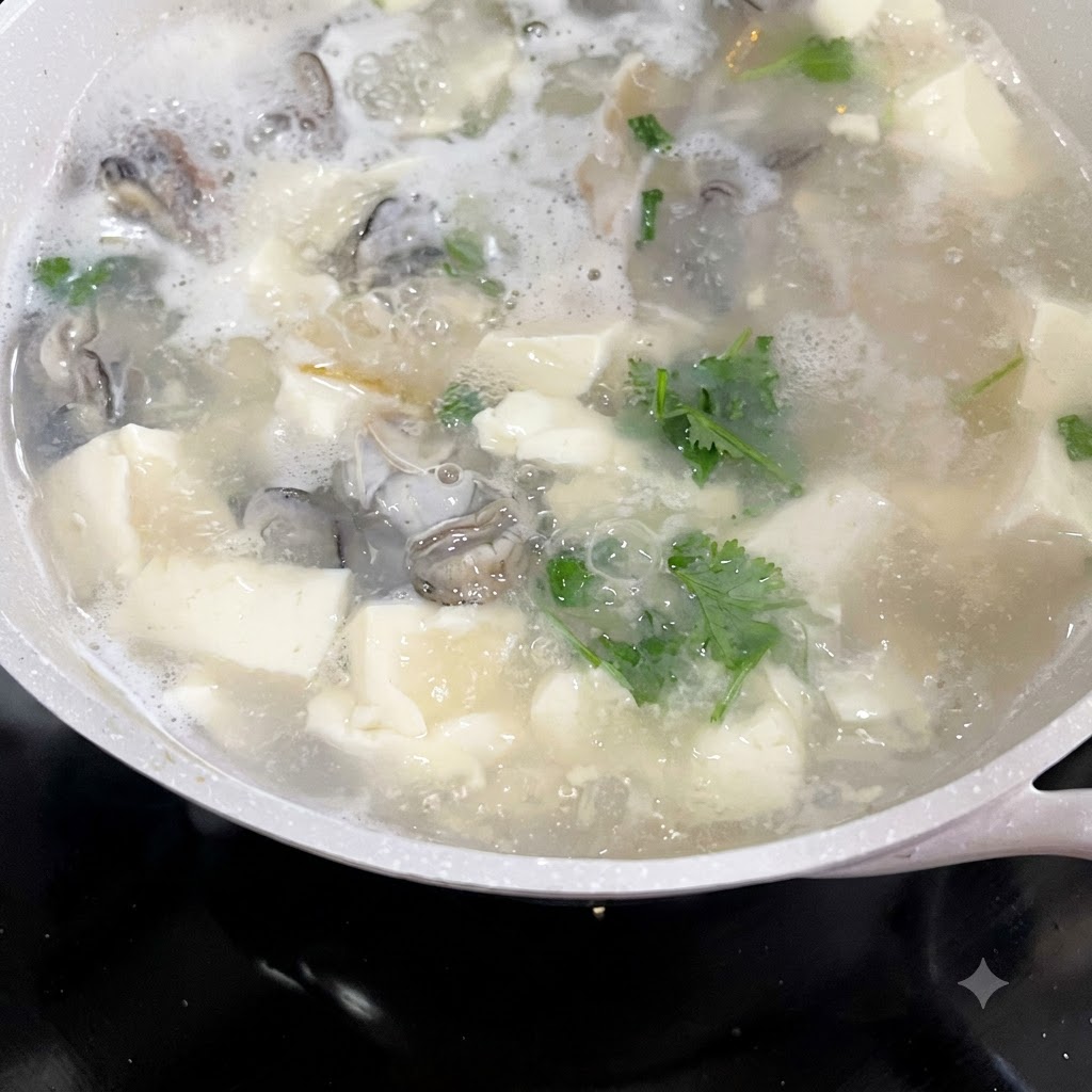 Gehackter Koriander und Frühlingszwiebeln werden in einen blubbernden Topf mit Austern-Tofu-Suppe gegeben.