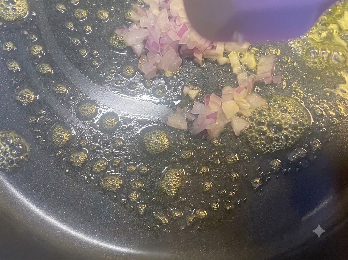 Gewürfelte rote Zwiebeln werden in einer Bratpfanne mit geschmolzener Butter und einem Holzspatel angebraten.