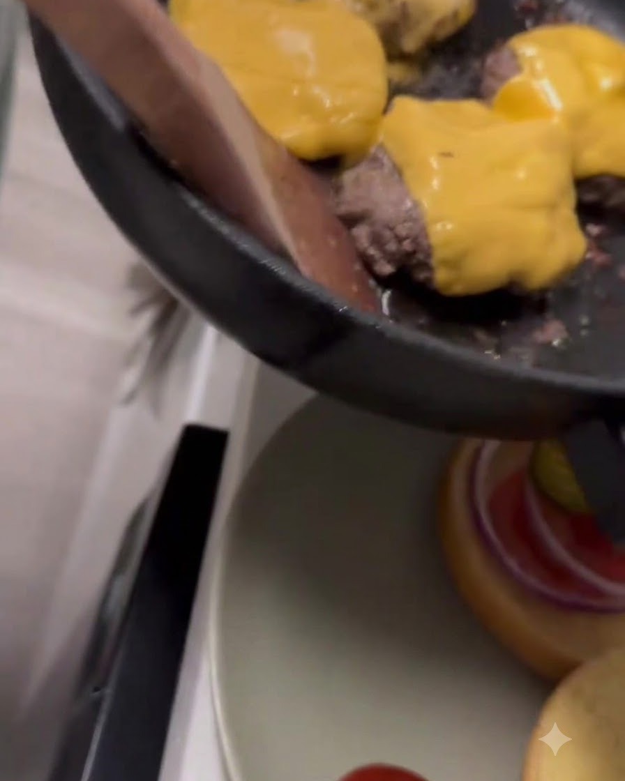 Gelber Cheddar-Käse schmilzt auf den Rindfleisch-Patties in einer Pfanne.