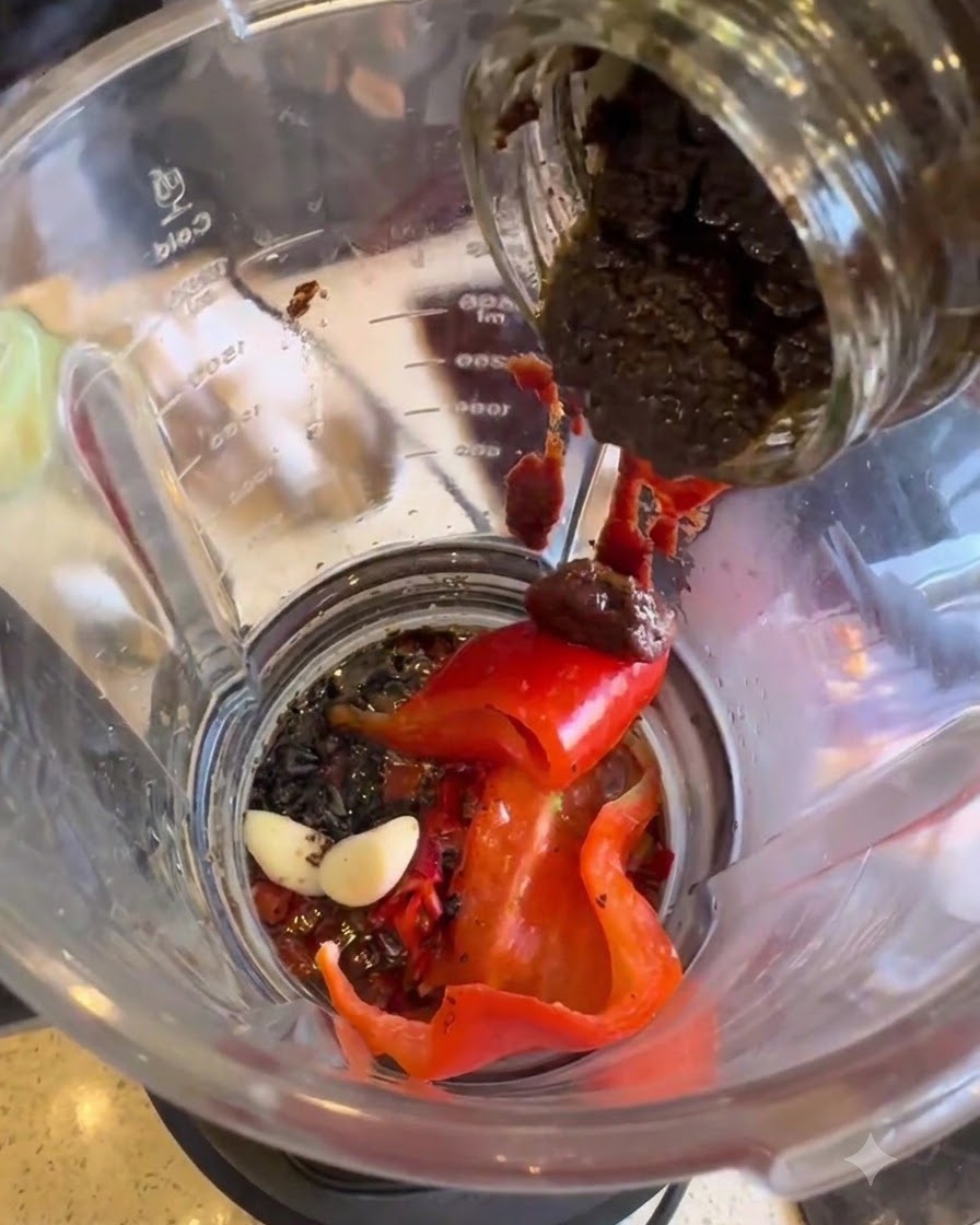 Schwarze Trüffelpaste wird aus einem Glas in den Mixer gefüllt.
