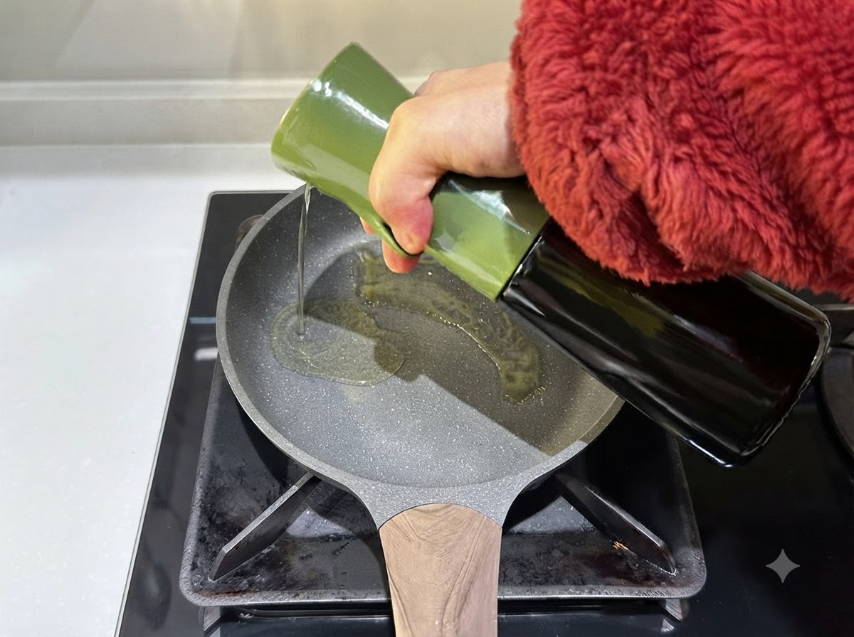 Olivenöl wird aus einem grünen Behälter in eine heiße Bratpfanne gegossen.