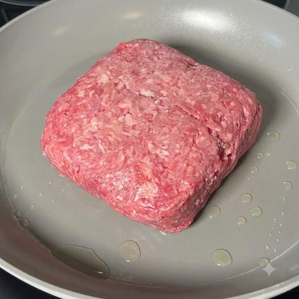 Rinderhackfleisch wird in einer breiten Pfanne mit einem Holzspatel gekocht und zerkleinert.