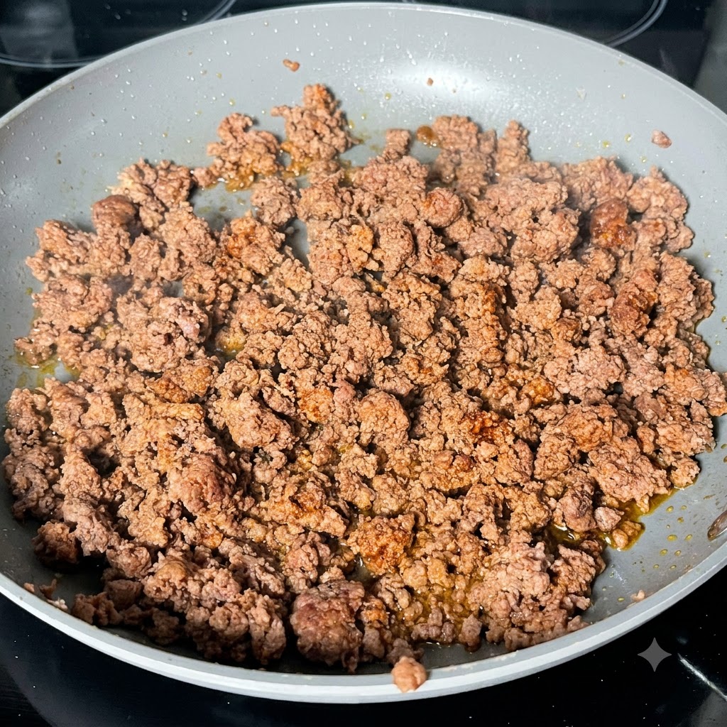 Dunkle Worcestersauce wird in einer Pfanne auf angebratenes Hackfleisch geträufelt.